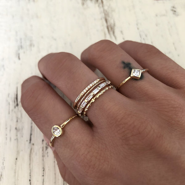 A female model’s hand showcasing a layered look of multiple Kurafuchi gold rings over several fingers.