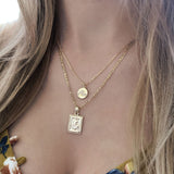 A female model wearing a layered look of gold pendant necklaces by Kurafuchi Jewelry.