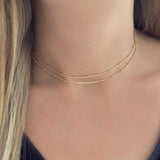 A female model wearing a gold double-strand chain necklace by Kurafuchi Jewelry.