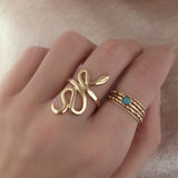 A female model’s hand featuring a stacked combination of various gold Kurafuchi rings over several fingers.