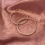 Dainty large textured gold hoop earrings. By Kurafuchi.