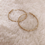 Dainty large textured gold hoop earrings. By Kurafuchi.
